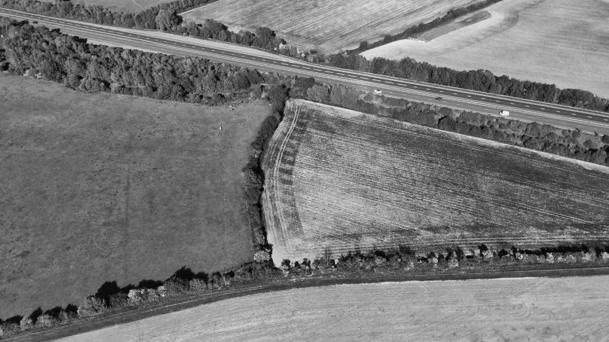 Drone aerial shot of fields and highway in the English countryside, highlighting rural landscape.