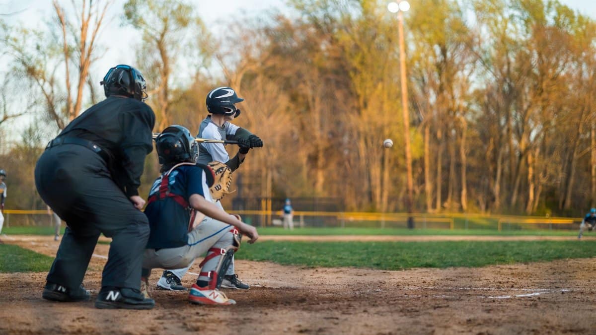 A lively scene of a youth baseball game featuring a batter, catcher, and umpire in action on the field.