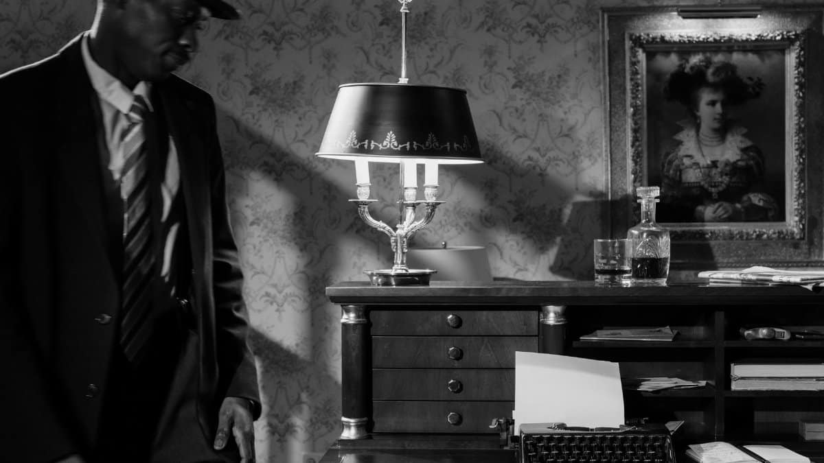 Moody black and white photo of a detective in a vintage office, evoking classic noir cinema.