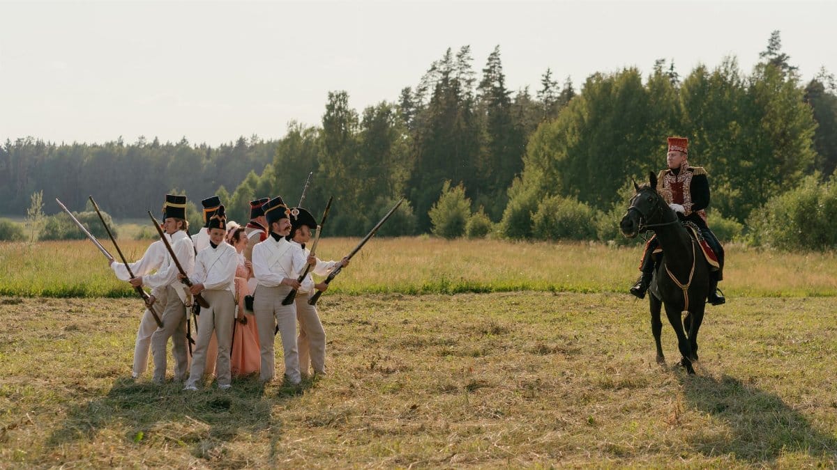 A group of soldiers in historical uniforms participating in a reenactment, featuring a horseback rider.