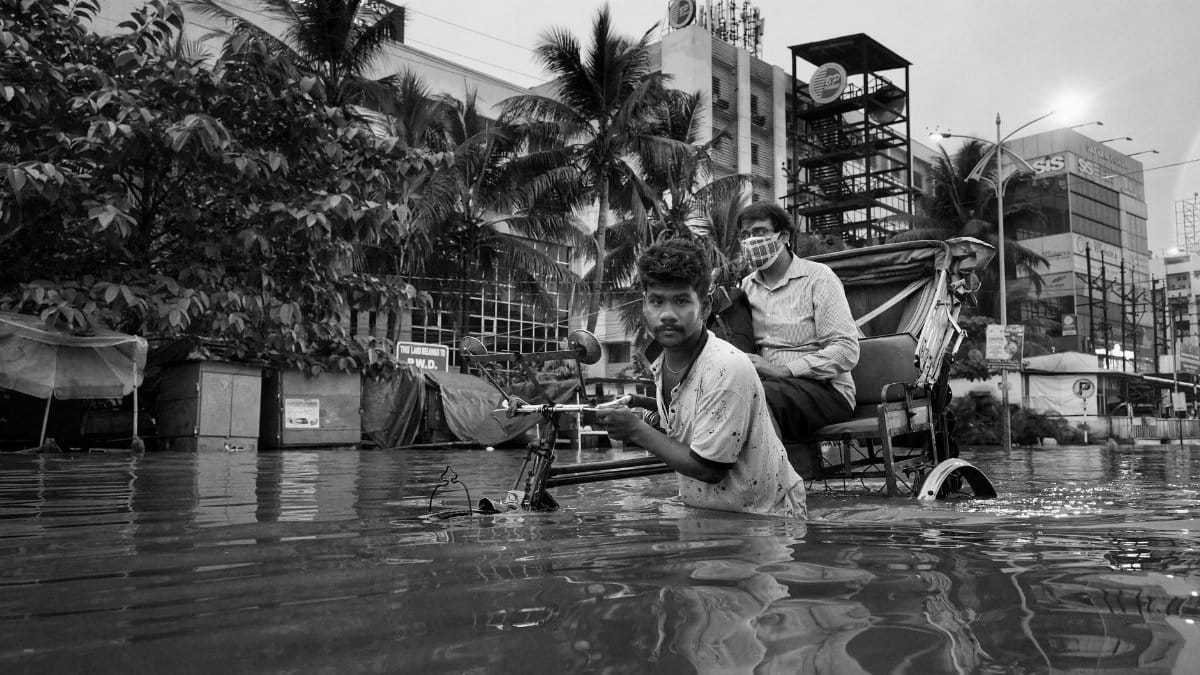 A rickshaw pulls through flooded city streets in Kolkata, India, showcasing urban life challenges.