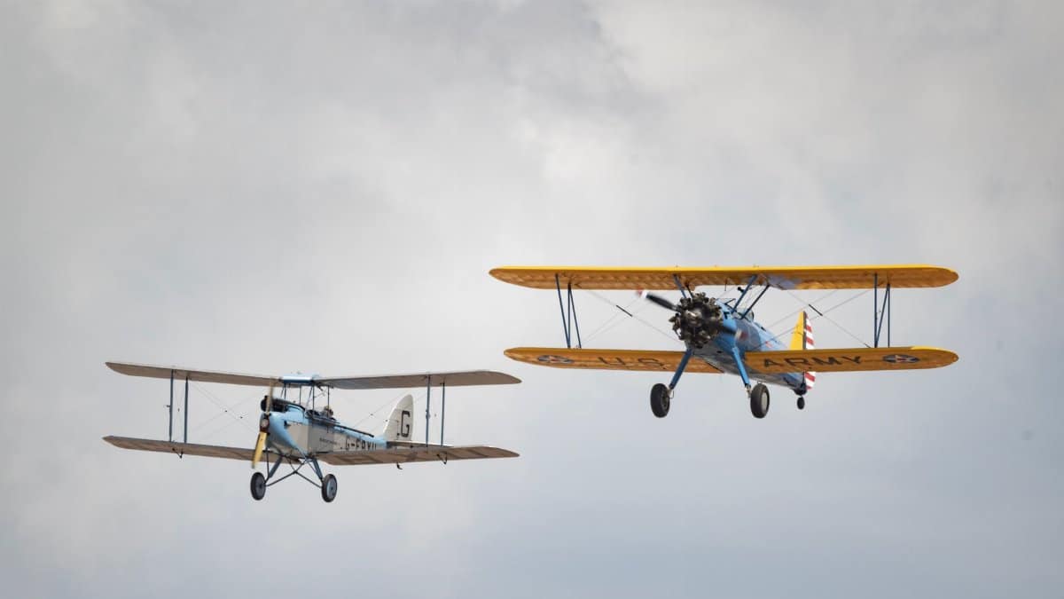 Two vintage biplanes flying in a cloudy sky, showcasing historical aviation.