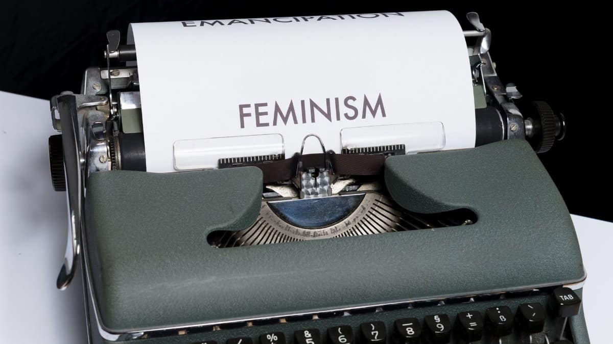 A retro typewriter with 'Feminism' and 'Emancipation' messages on paper.