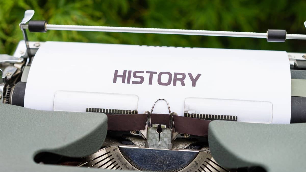 Close-up of a vintage typewriter with a paper labeled 'History' in an outdoor setting.