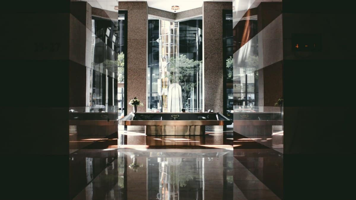 A sophisticated modern hotel lobby with glossy floors and natural light entering through large windows.