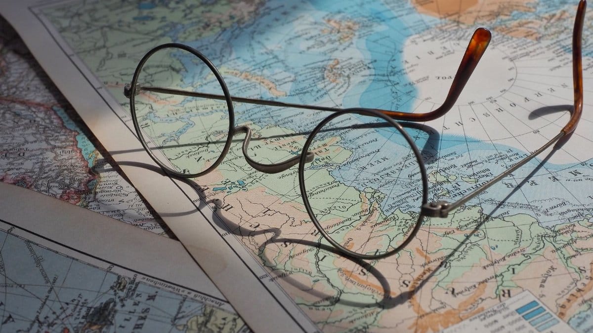 Round vintage eyeglasses resting on a vibrant historical world map, capturing a sense of exploration.