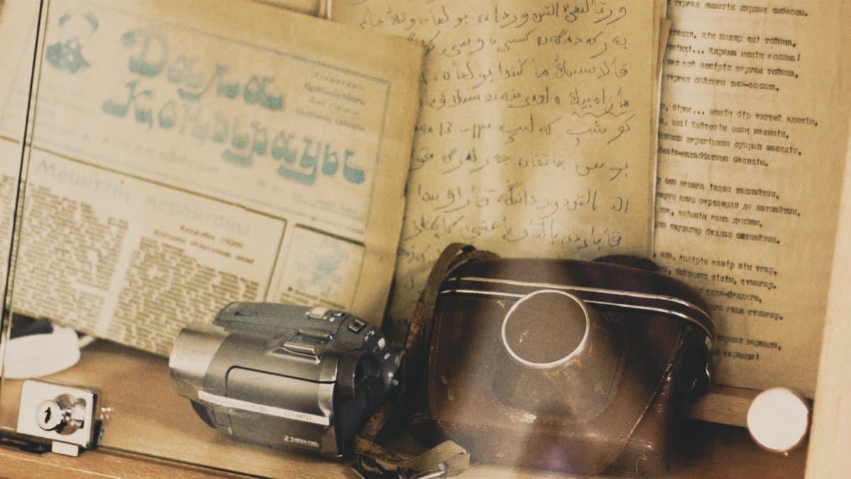 Retro camera and historical scripts under glass, evoking nostalgia.