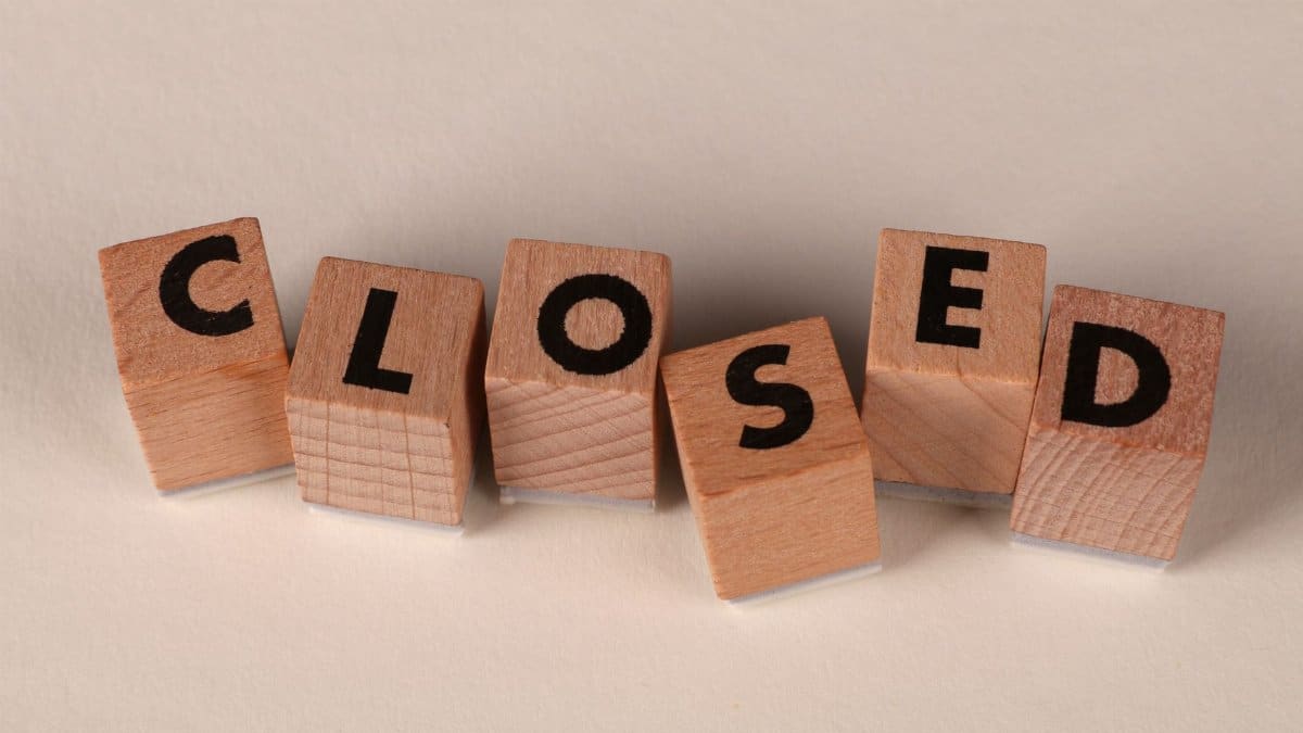 Wooden blocks spell 'closed' on a beige background, symbolizing closure or shut down.