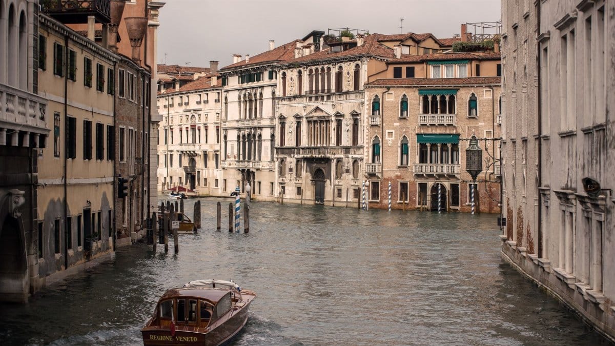 Charming Venice canal view with historical architecture and a boat cruising on a calm day.