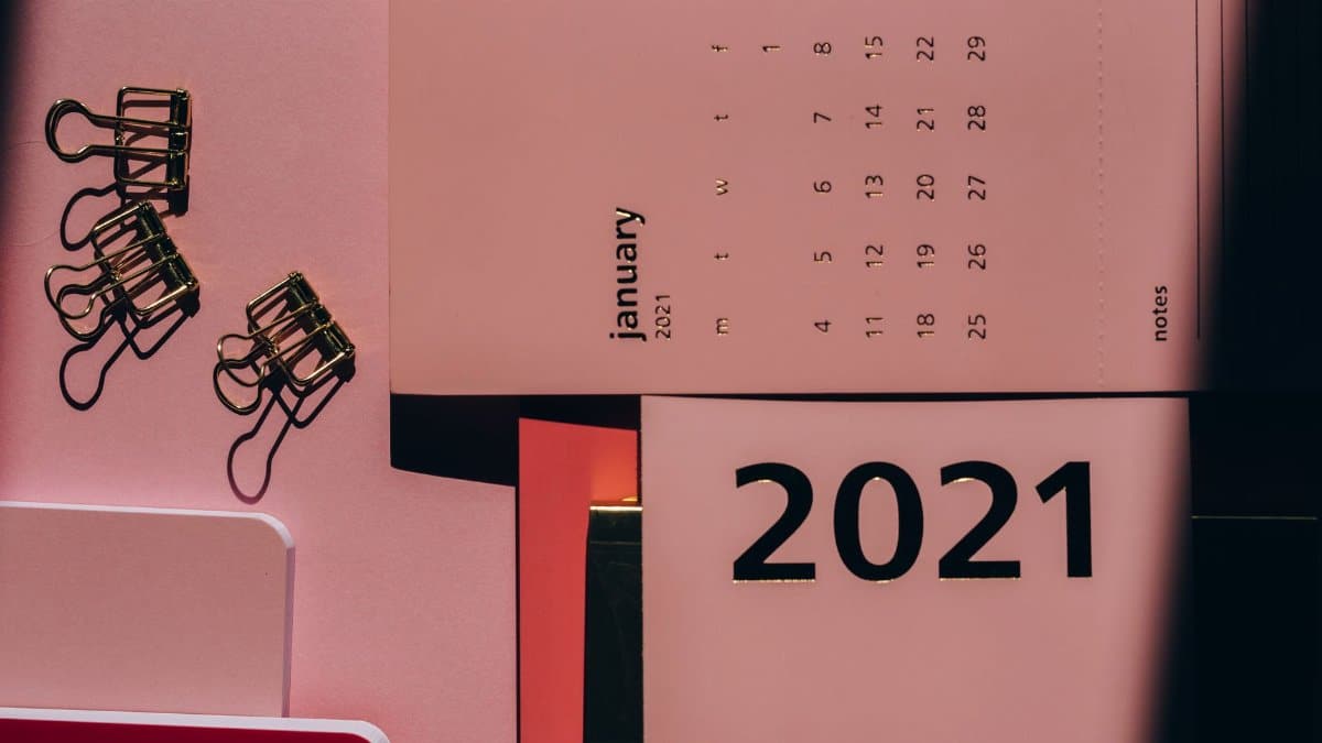 Overhead view of contemporary calendar with weekly dates near metal clips on office desk