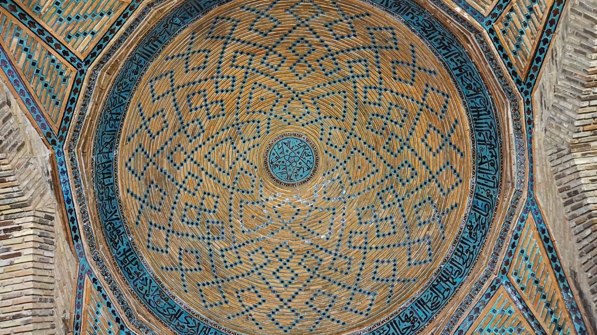 Beautifully detailed Islamic dome showcasing geometric patterns and Arabic calligraphy.