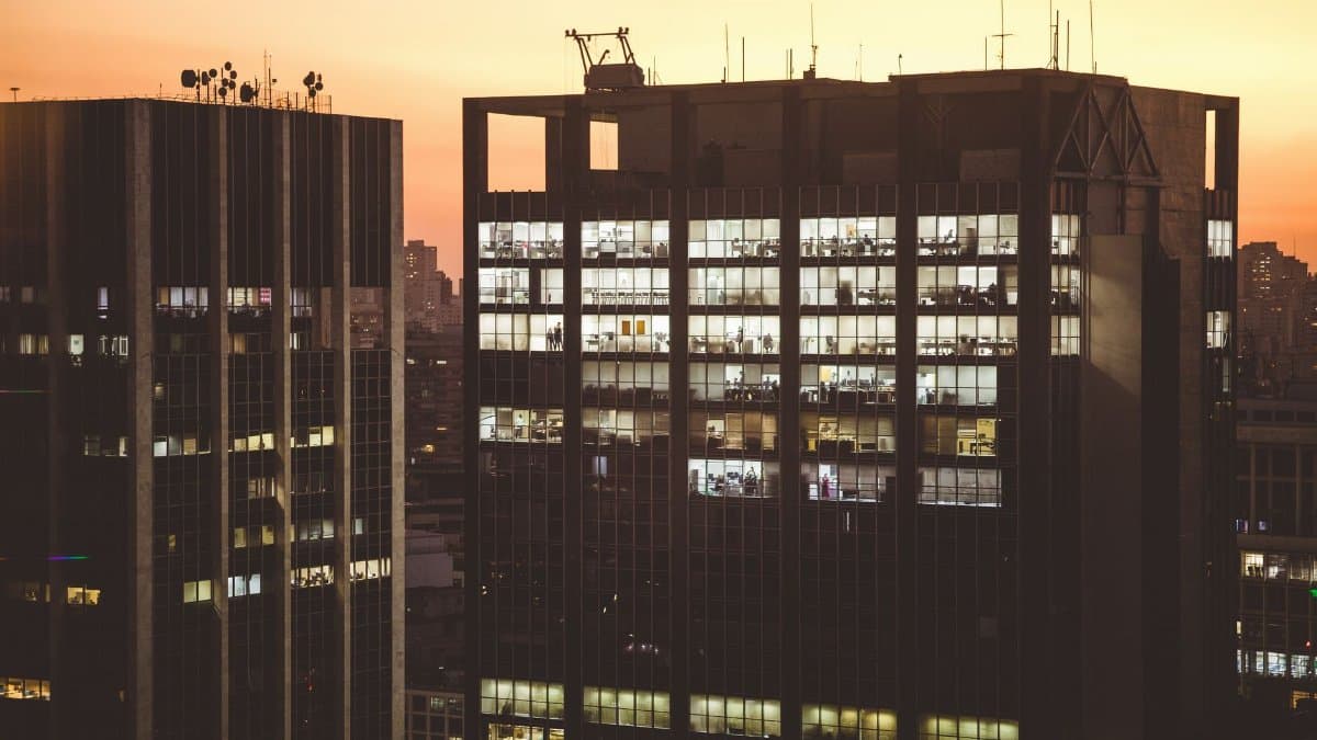 City office buildings illuminated against a sunset backdrop, showcasing urban life.