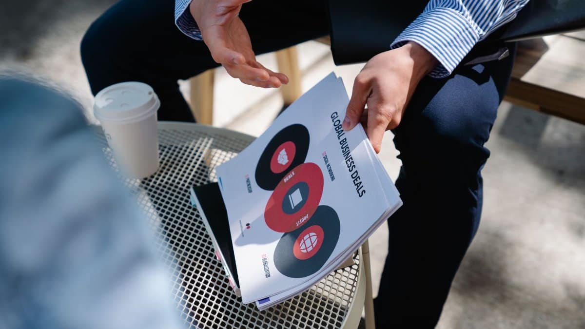 A businessman discusses global business deals with visual aids during an outdoor meeting.