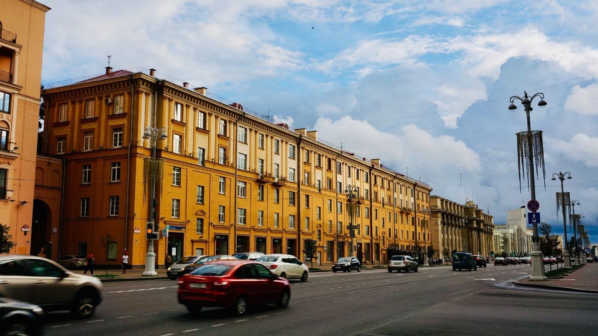 Colorful urban street scene with historical buildings and traffic under a cloudy sky.