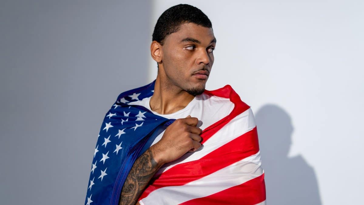 Portrait of a man wrapped in the American flag symbolizing patriotism and pride.