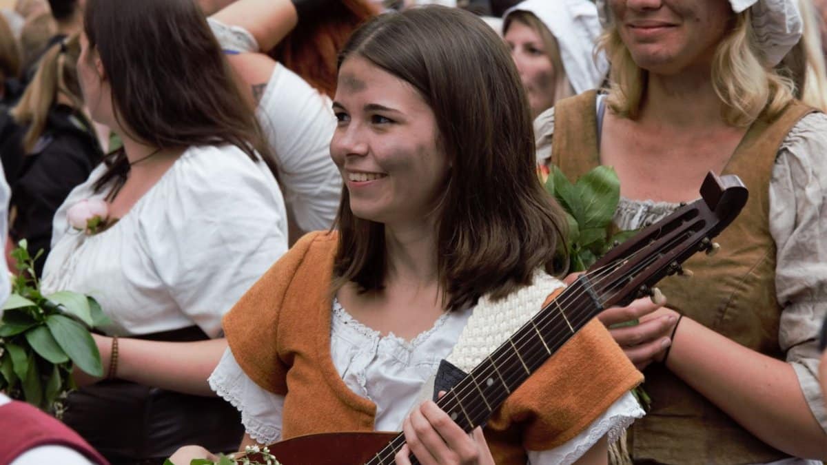Group of women in medieval attire enjoying a festive outdoor event with music.