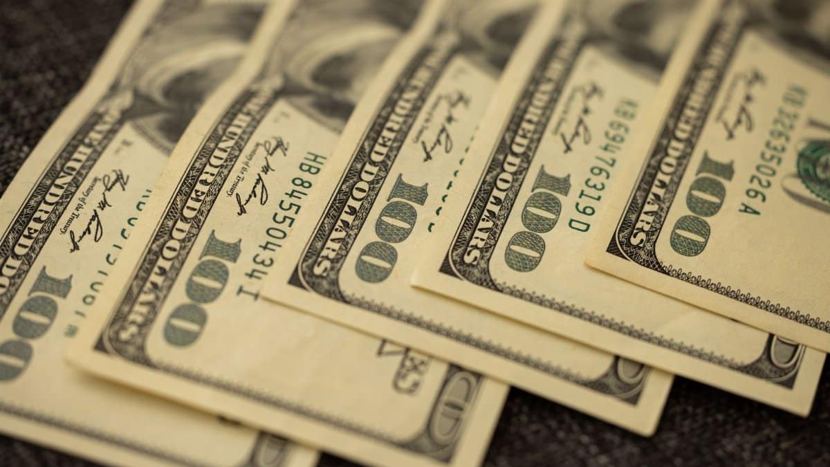 A detailed view of stacked US hundred dollar bills in a close-up shot.