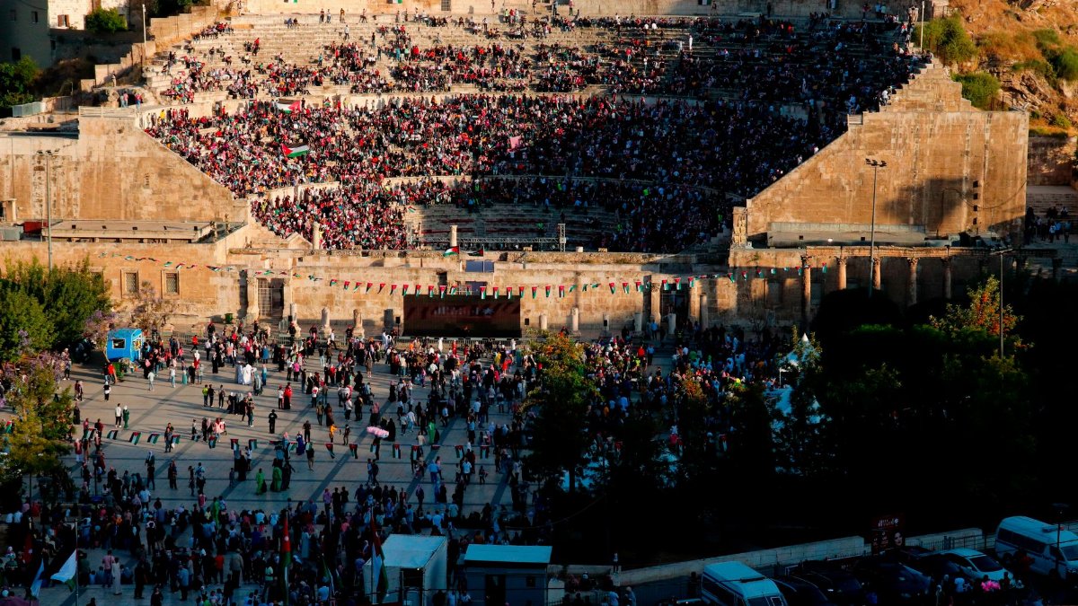 Aerial view of a large crowd gathered at the Roman Theatre in Amman, highlighting its ancient architecture.