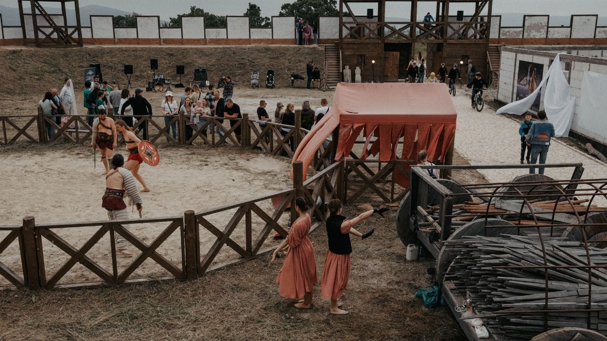 Lively medieval reenactment event featuring gladiators and spectators in outdoor arena.