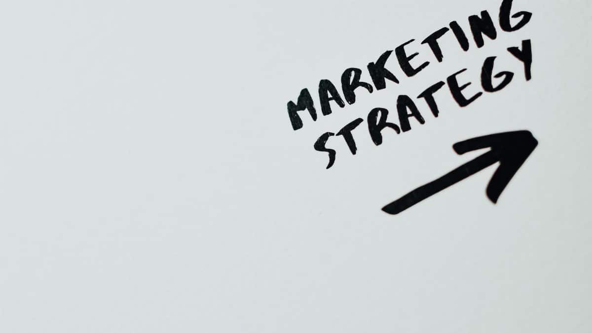 Close-up of handwritten 'Marketing Strategy' text with an arrow on white background.