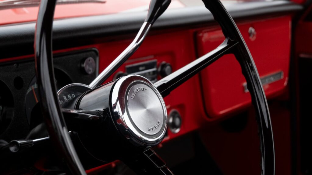 Close-up view of a classic Chevrolet steering wheel in a vintage red truck in Alto, Michigan.