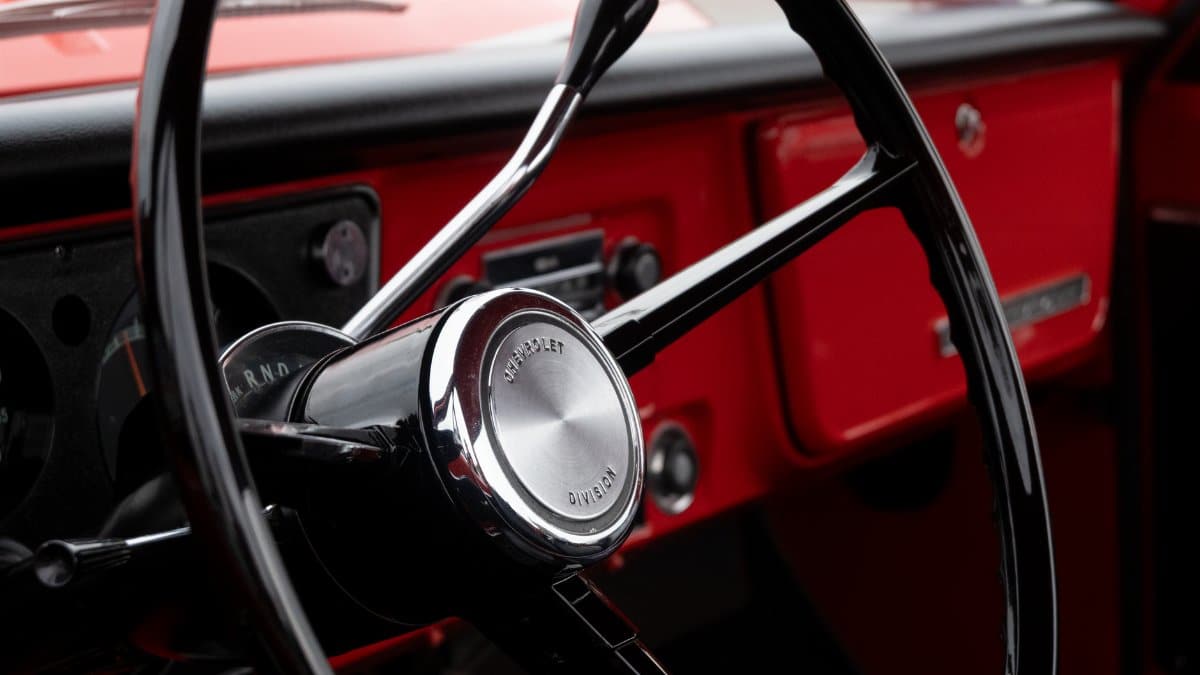 Close-up view of a classic Chevrolet steering wheel in a vintage red truck in Alto, Michigan.