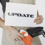Close-up of a gardener holding an 'Update' sign and tools, symbolizing change.