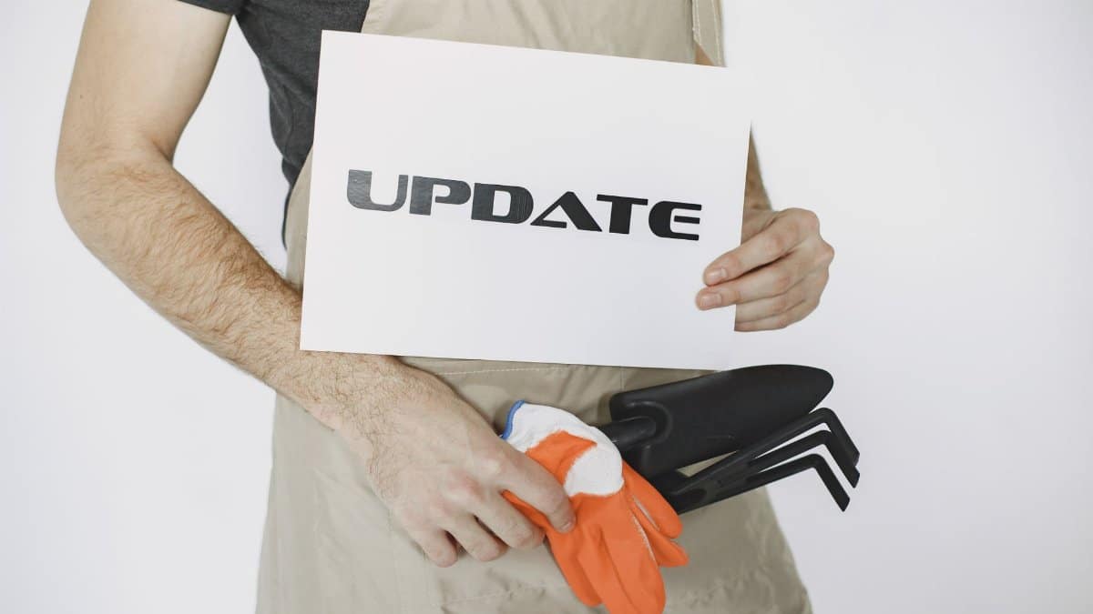 Close-up of a gardener holding an 'Update' sign and tools, symbolizing change.