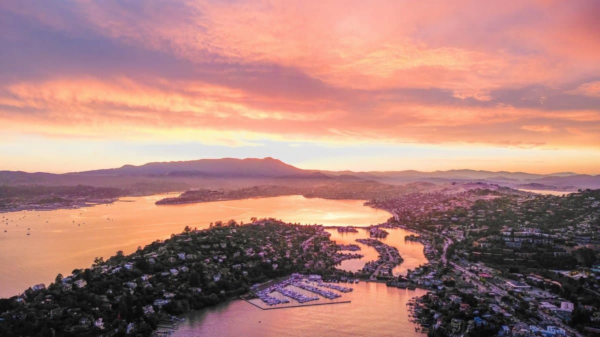 A breathtaking aerial view of a sunset over Marin County's coastline, capturing vibrant sky colors and water reflections.