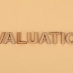Wooden letter blocks arranged to spell 'evaluation' on a beige background.