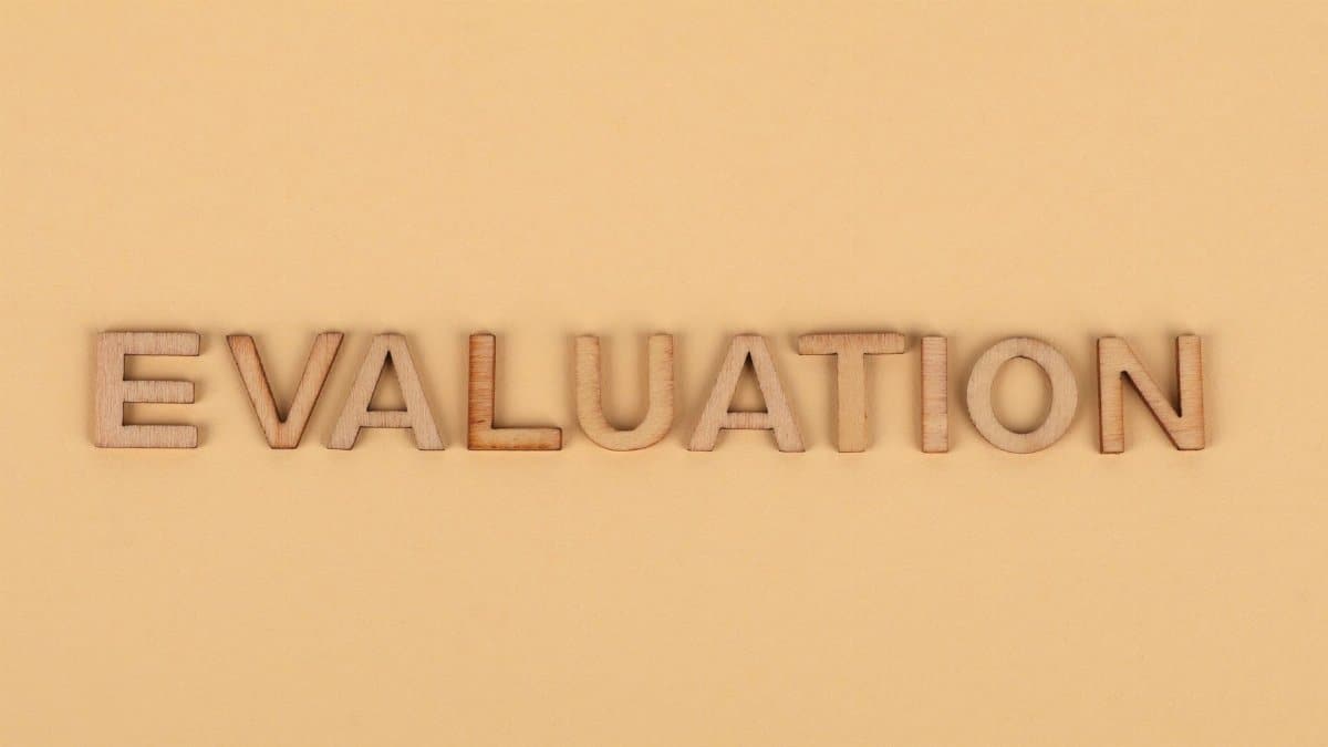 Wooden letter blocks arranged to spell 'evaluation' on a beige background.