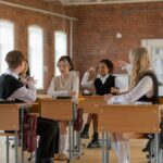 A diverse group of students wearing uniforms interacting in a classroom, emphasizing school life and education.