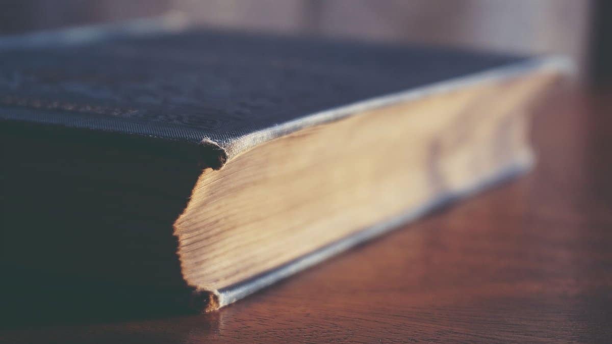 Close-up view of an old book with visible paper texture on a wooden table.