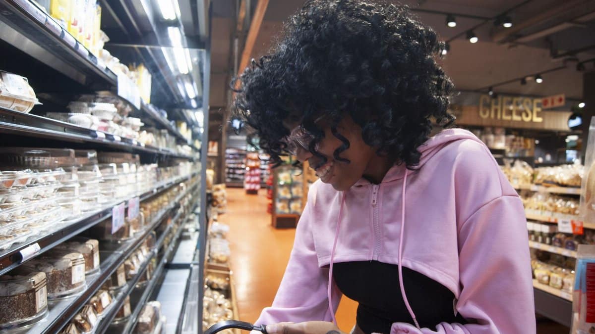 Young adult shopping in a well-lit grocery store, choosing groceries from the shelves.