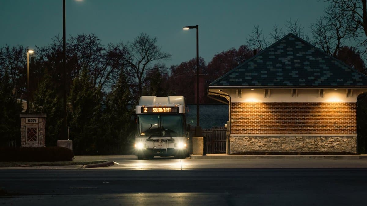 Illuminated public bus on a quiet city street during twilight hours.