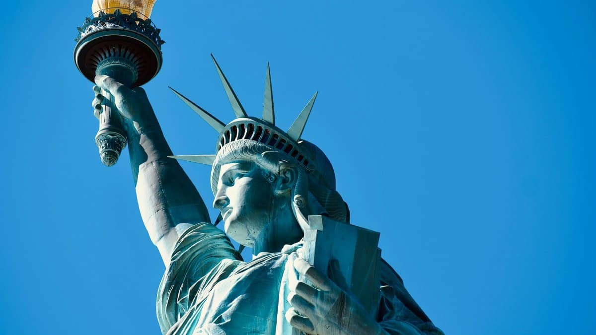 Close-up of the Statue of Liberty's torch and face against a clear blue sky in New York.