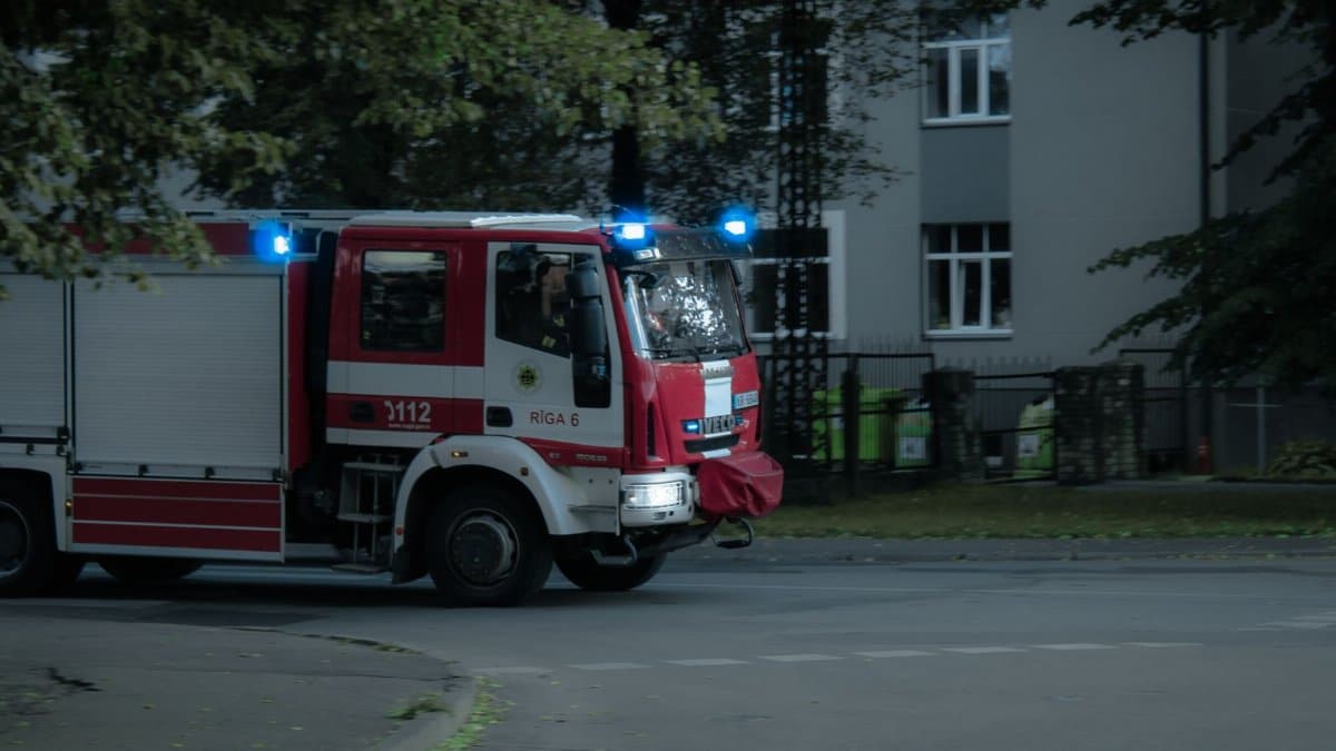 Red and white fire truck with flashing lights responding to an emergency in an urban area.