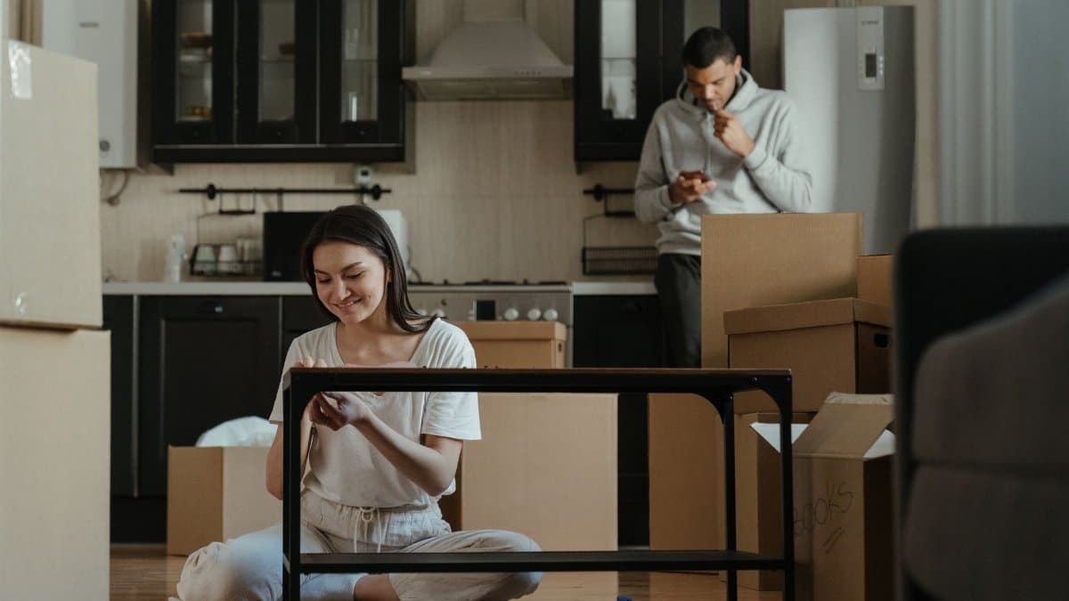 A young couple unpacking boxes in their new apartment kitchen, settling into a cozy home.