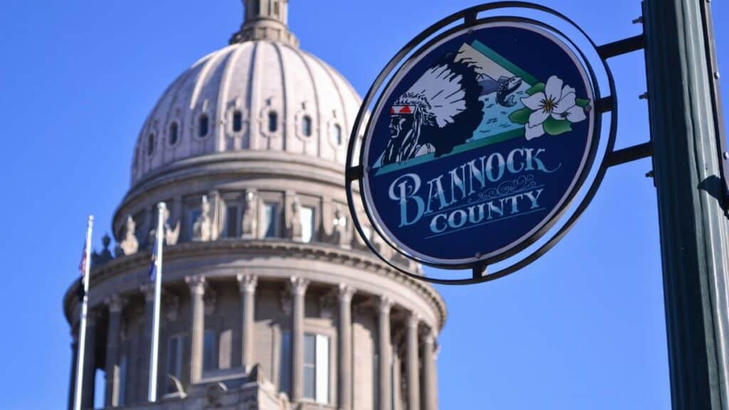 Idaho State Capitol Building dome with Bannock County sign under a clear blue sky in Boise.