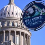 Idaho State Capitol Building dome with Bannock County sign under a clear blue sky in Boise.