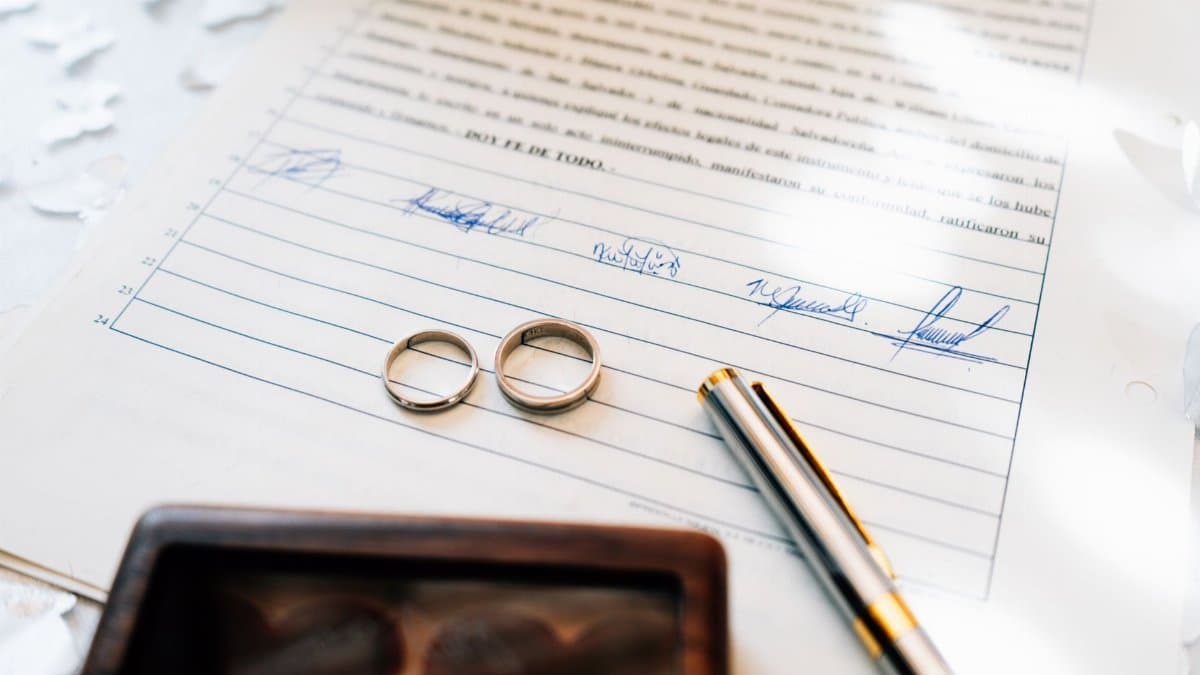 Elegant wedding rings laid on a signed marriage certificate, symbolizing commitment.