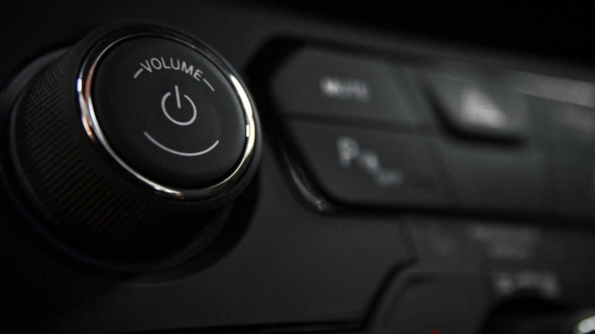 Detailed close-up of a vehicle's volume control knob and dashboard buttons indoors.
