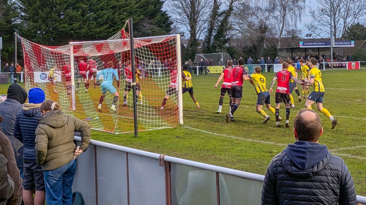 Action-packed amateur football match in progress, England. Enthusiastic crowd cheering.