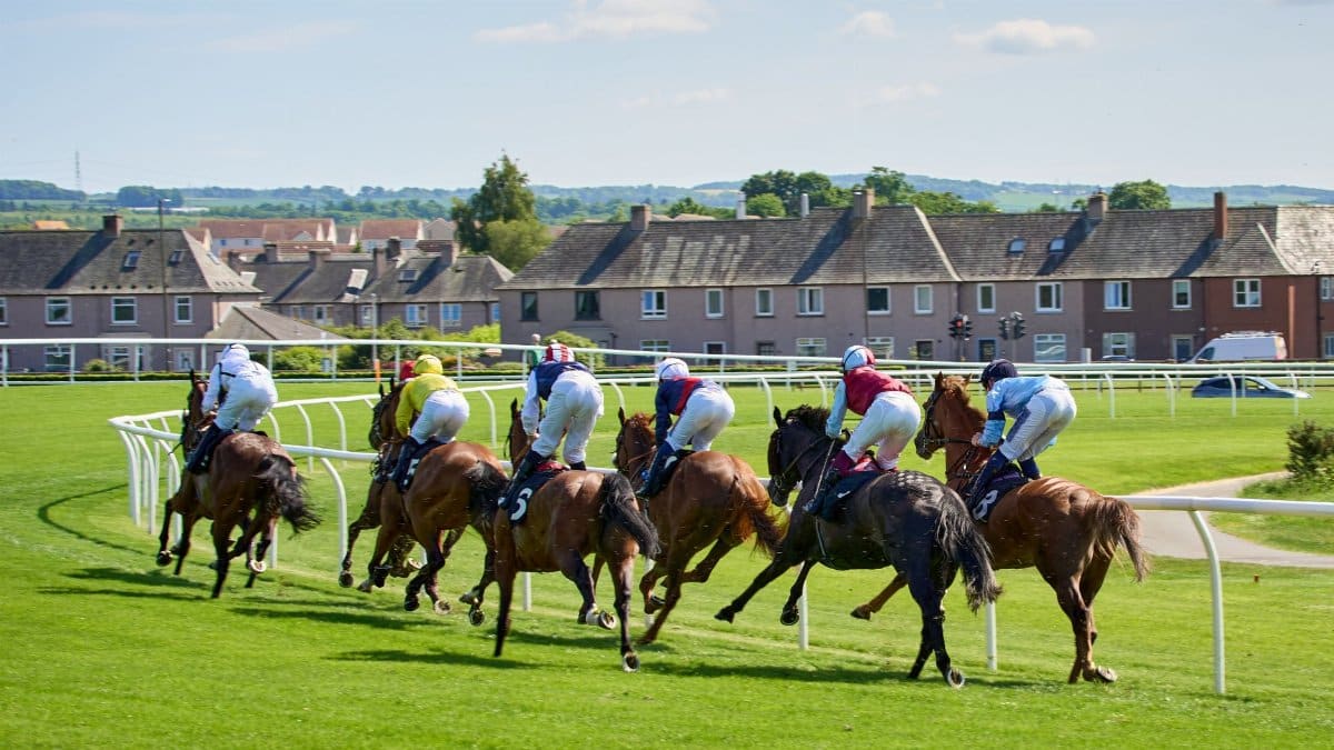 Dynamic shot of a horse race in Musselburgh with jockeys in colorful attire.