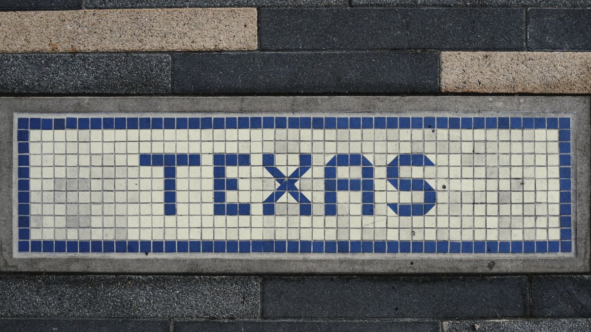 Unique mosaic tile artwork spelling 'Texas' on a sidewalk in Houston, TX.
