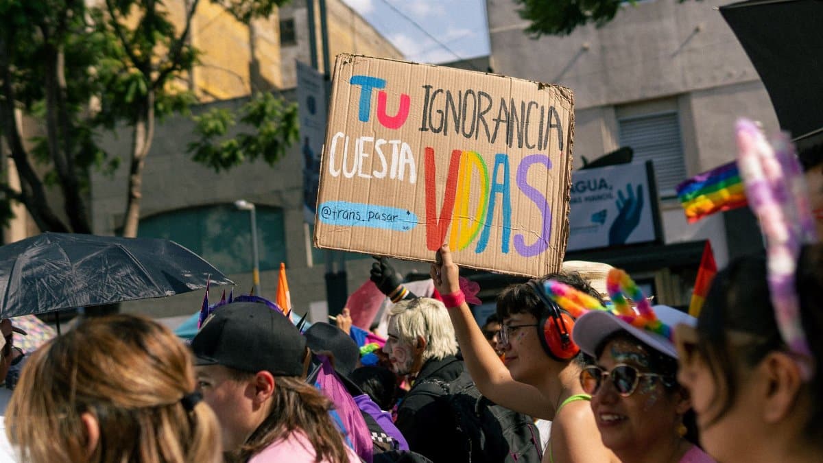 Colorful pride march scene featuring protest signs and diverse participants celebrating LGBTQ rights.