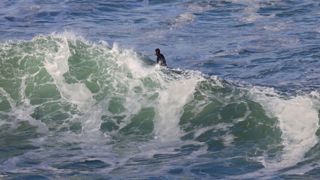 A surfer skillfully navigates a massive ocean wave, showcasing adventure and agility.