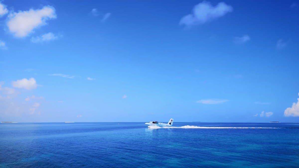 Vibrant image of a hydroplane gliding over the clear blue waters of the Maldives under a bright sky.