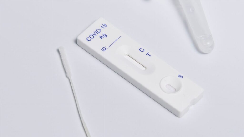 Close-up of a COVID-19 rapid antigen test kit showing the testing strip and swab.