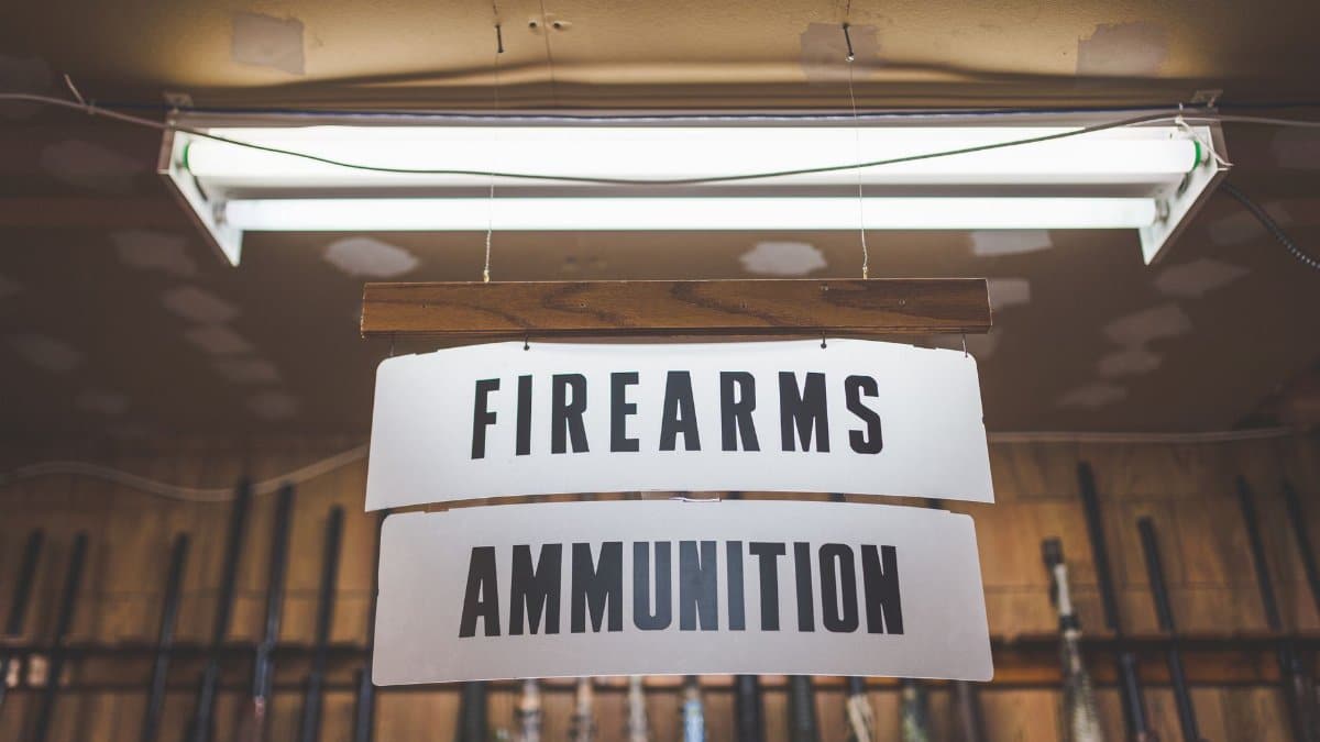 Hanging indoor signage for firearms and ammunition store, with visible lighting.